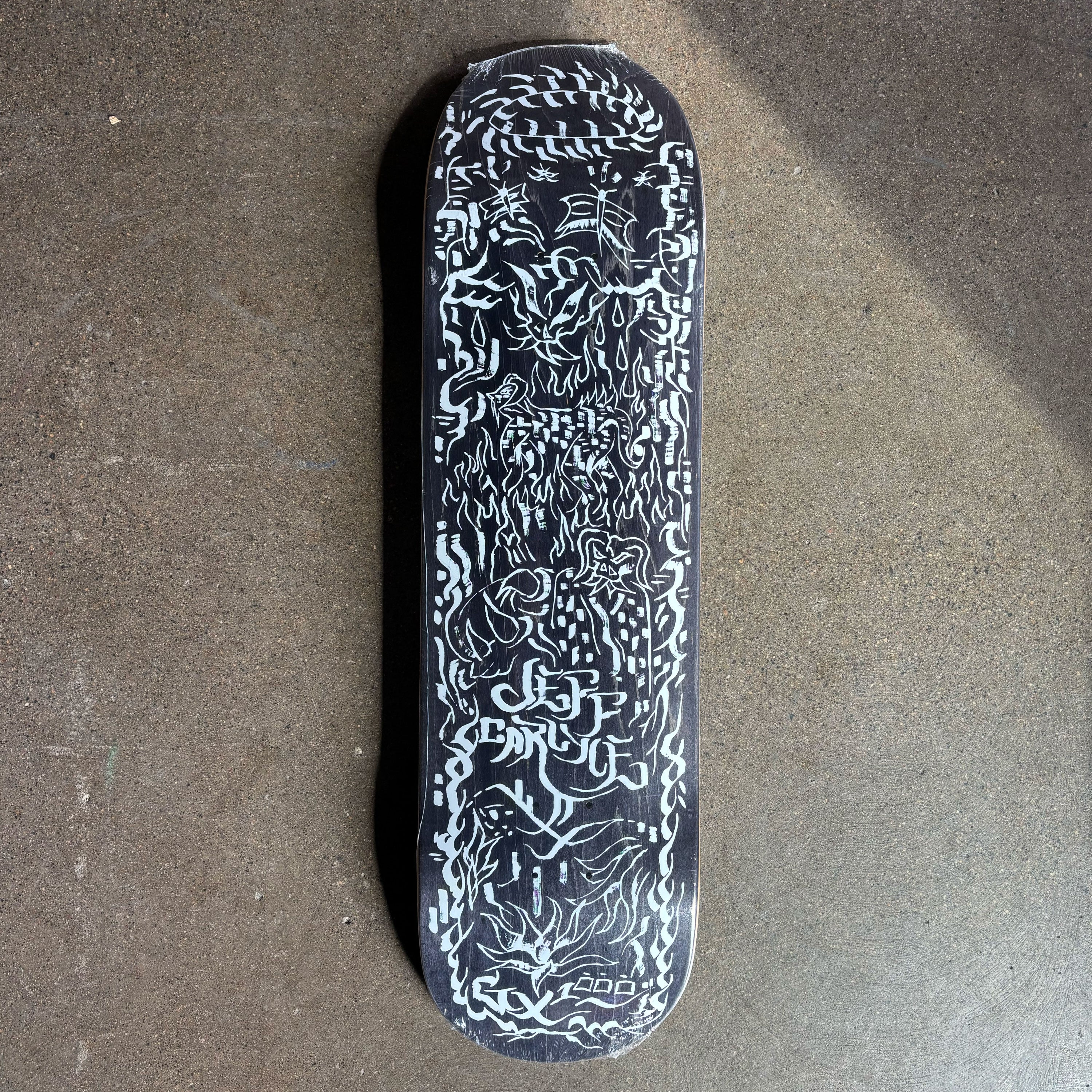 Full image of black deck with white chaos art throughout.